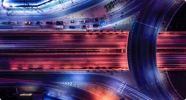 Night aerial view of highway interchange with light trails